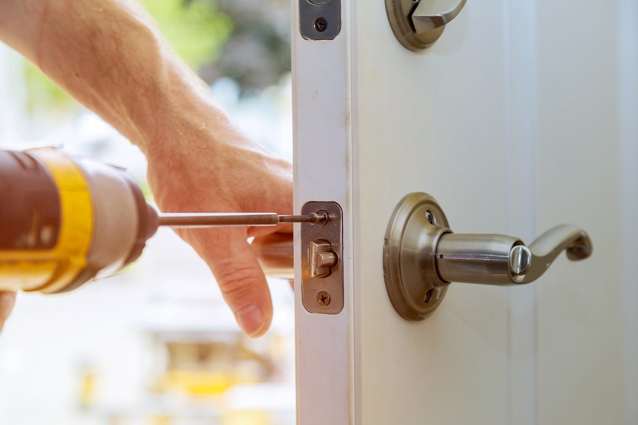 Installation locked interior door knobs, close-up woodworker hands install lock.